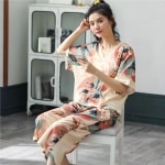 Pyjama d'été deux pièces avec col en V et motif floral portée par une femme assise sur une chaise dans une maison