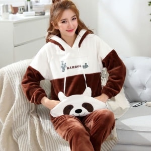 Pyjama femme deux pièces en flanelle à motif panda avec une femme qui porte le pyjama et un fond un canapé gris avec une couverture blanche