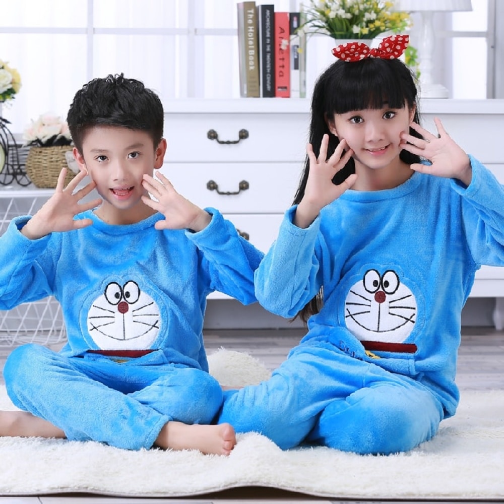 Pyjama en flanelle à manches longues bleue avec imprimé Doraemon pour enfant assise sur un tapis dans une maison