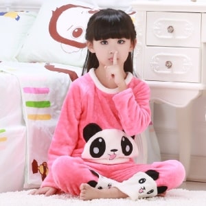 Pyjama rose deux pièces à motif panda pour fille portée par une petite fille assise sur un tapis devant un lit dans une maison