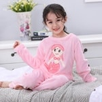 Pyjama en flanelle manches longues à motif sirène pour fille portée par une petite fille sur un lit dans une maison