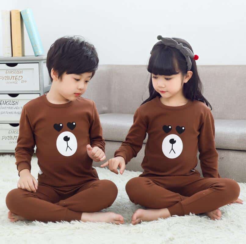 Pyjama printemps marron à motif ours pour enfants avec deux enfants qui porte le pyjama et un fond un canapé