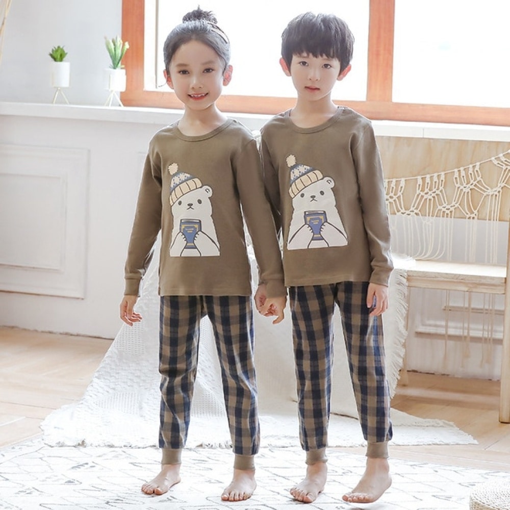 Pyjama printemps avec pull-over beige et pantalon carreaux pour enfants avec deux enfants qui porte le pyjama est un fond une chambre