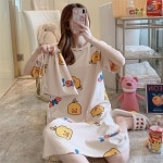 Pyjama robe de nuit avec imprimé dessin animé pour femmes portée par une femme assise sur un tapis dans une maison