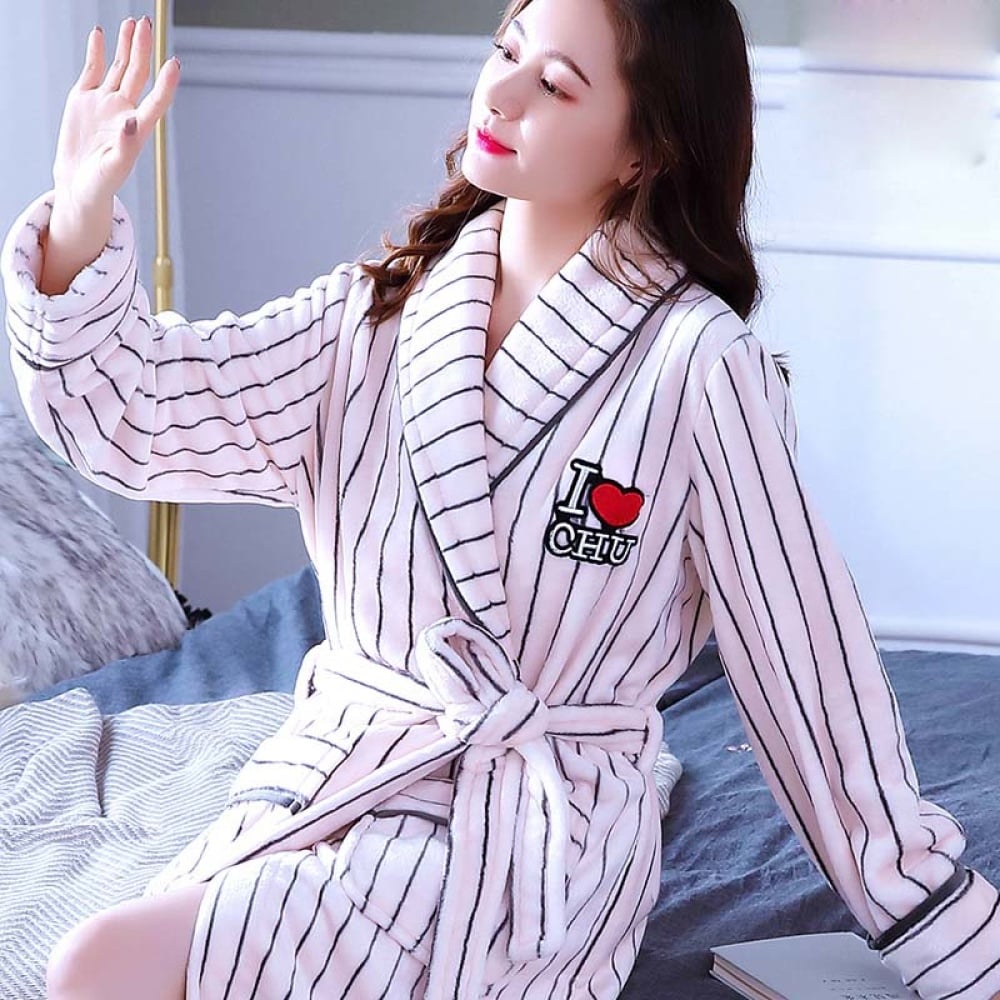 Pyjama en molleton de corail blanc rayé noir pour femmes porté par une femme assise sur un lit dans une maison