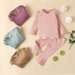Pyjama simple en coton pour petites filles avec plusieurs pyjamas qui sont pliés et un fond beige