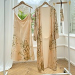 Pyjama sexy beige à imprimé floral suspendus à des cintres dans une pièce avec parquet et mur blanc et devant une fenêtre ouverte