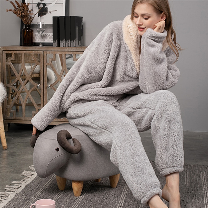 Pyjama polaire de couleur gris porté par une femme assise sur un siège à la forme d'un mouton dans un salon aux murs et sols gris