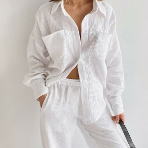 Pyjama blanc en coton porté par une femme contre un mur blanc