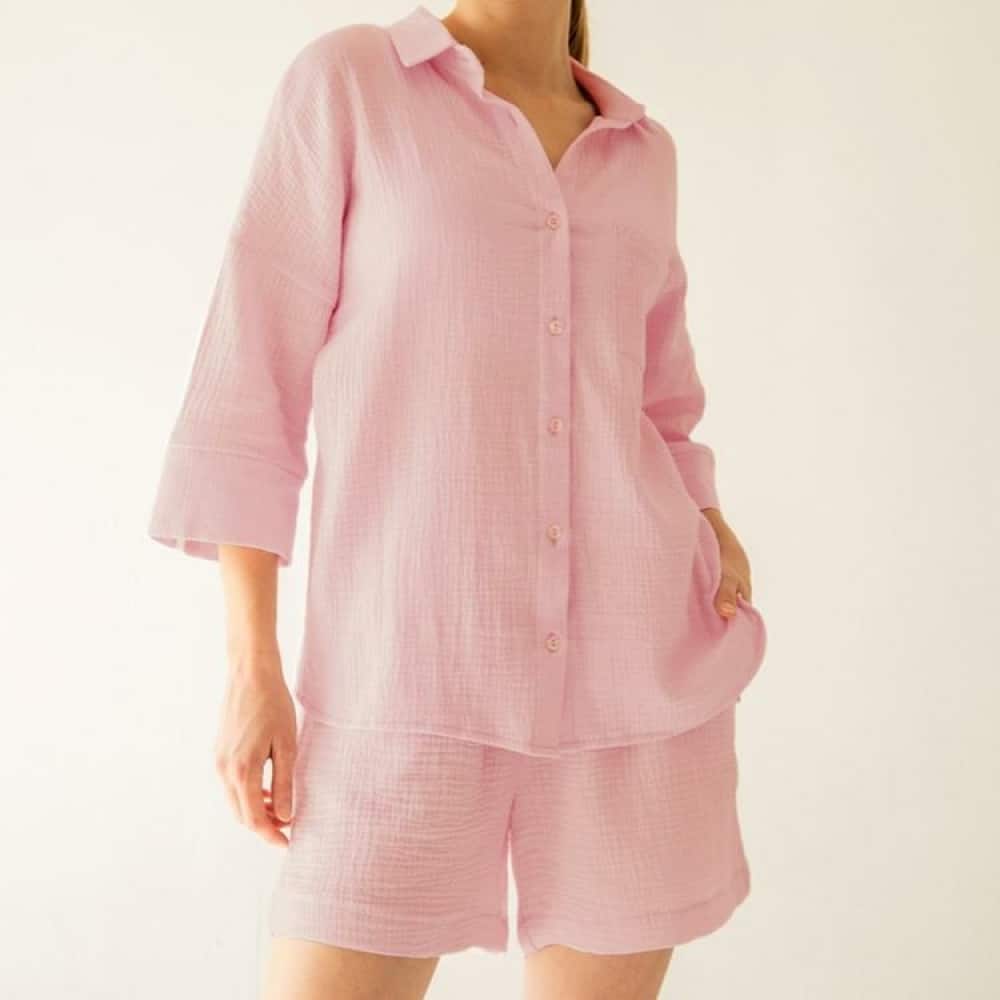 jeune fille qui porte un pyjama rose composé d'une chemise à manche mi-longues et un short assorti