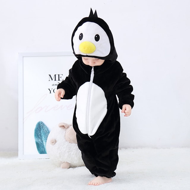 Bébé en pyjama combinaison noir en forme de pingouin qui regarde ses pieds