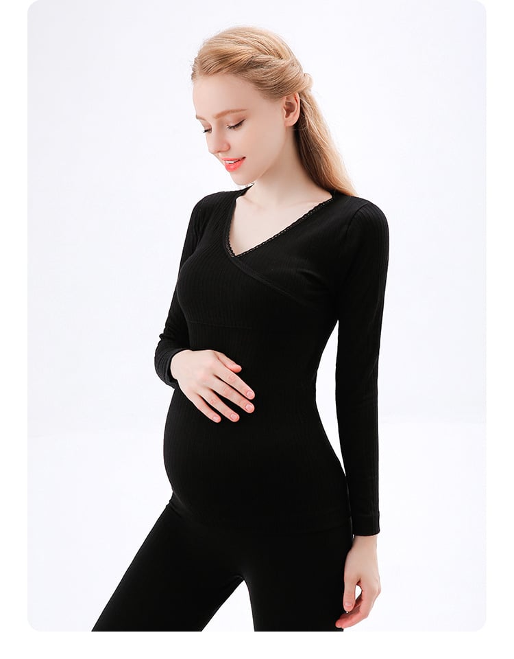 femme enceinte en train de se toucher le ventre d'une main , porte un pyjama noir composé d'un pantalon et d'un pull manche longue